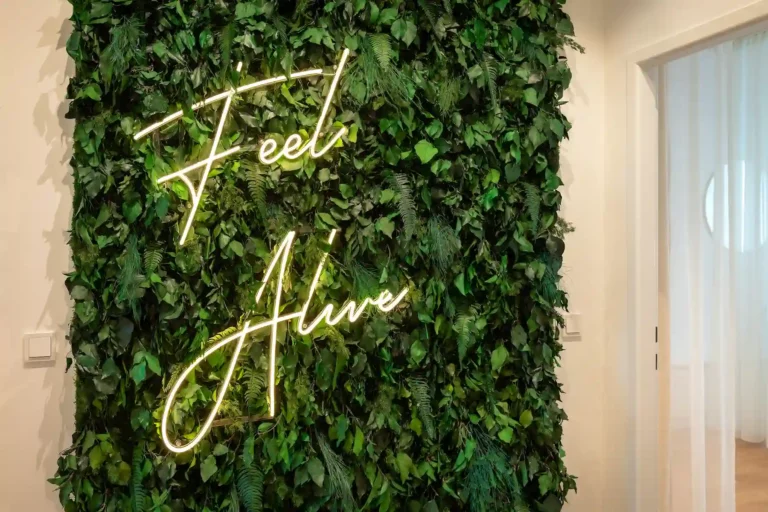 Pflanzenwand mit Neon-Schriftzug „Feel Alive“