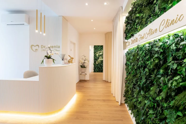 Empfangstheke der Feel Alive Clinic mit Logo und Pflanzenwand